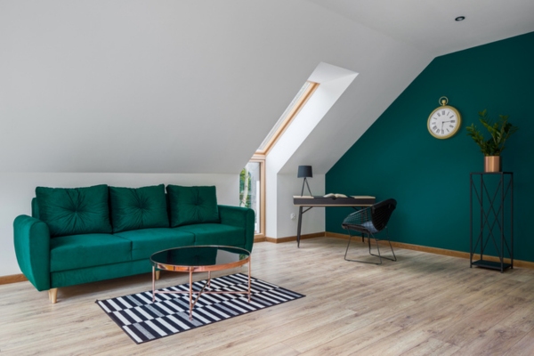 beautiful living room set up in the attic with emerald wall and couch
