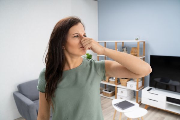 woman covering nose due to musty smells caused by AC molds