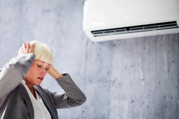 woman covering ear in front of ductless air conditioner depicting ignoring AC issues