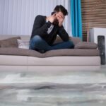 Flooded Floor In Front Of Man sitting on a couch