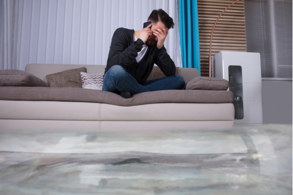 Flooded Floor In Front Of Man sitting on a couch