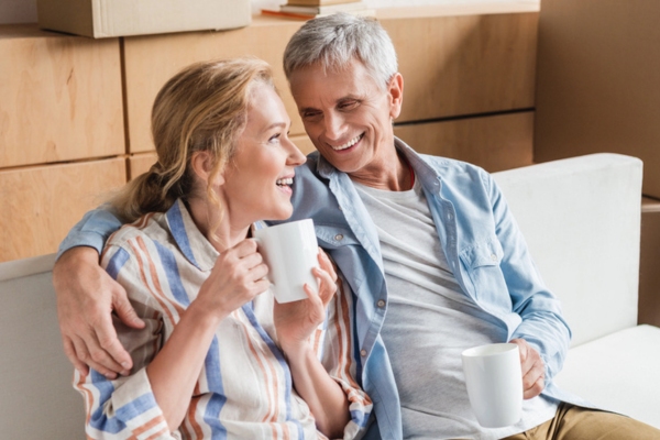 senior couple sitting on a couch while having coffee depicting peace of mind